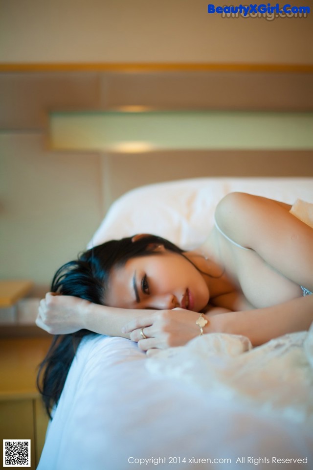 A woman laying on a bed with her head on the pillow.