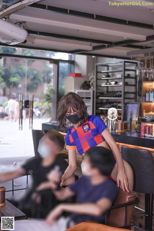 A woman wearing a face mask sitting at a table in a restaurant.