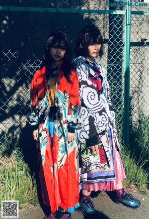 A couple of women standing next to each other on a bench.