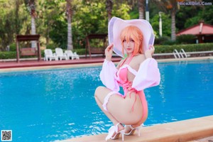 A woman in a pink bathing suit sitting by a pool.