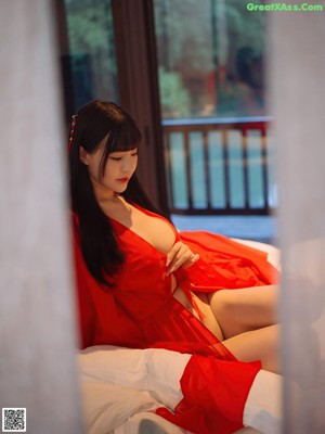 A woman in a red robe is posing for the camera.