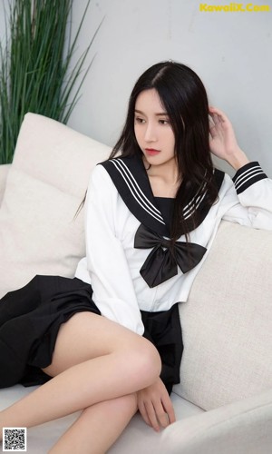 A woman in a sailor outfit sitting on a white couch.