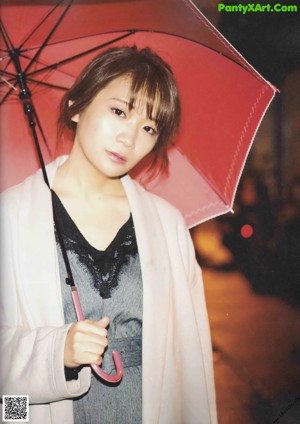 A woman standing in the middle of a street holding an umbrella.
