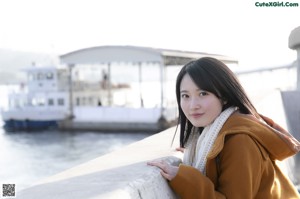 A young woman leaning against a wooden fence.