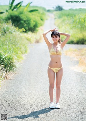 A woman in a pink bikini standing on a beach.