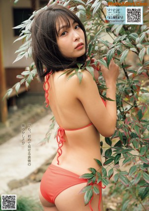 A woman in a bikini sitting on top of a barrel.