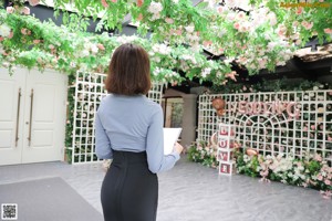 A woman in a blue shirt and black skirt talking on a cell phone.