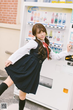 A woman in a school uniform leaning against a wall.