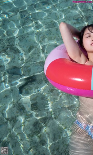 A woman in a pink bikini holding a blue towel over her head.