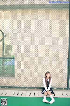 A woman sitting on a wooden floor next to a window.