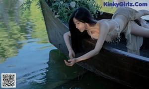 A woman sitting on a wooden bench next to a body of water.