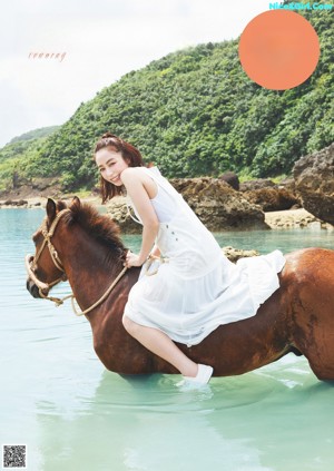 A woman in a brown dress sitting on a rock.