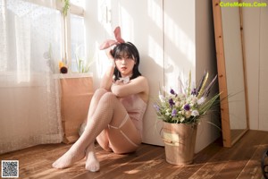 A woman in a pink bunny costume posing next to a mannequin.