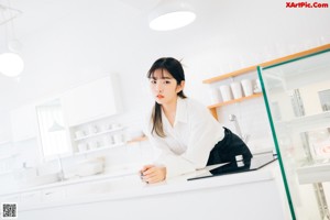 A woman sitting on top of a counter in a kitchen.