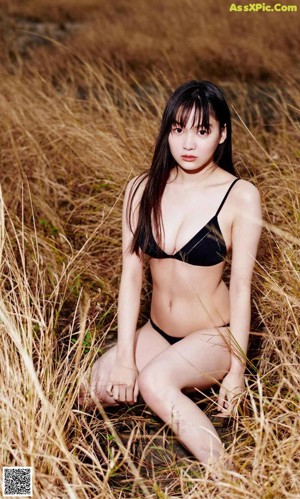 A woman with long black hair standing in a field.