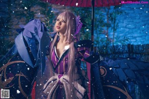 A woman dressed in a blue and purple outfit holding an umbrella.