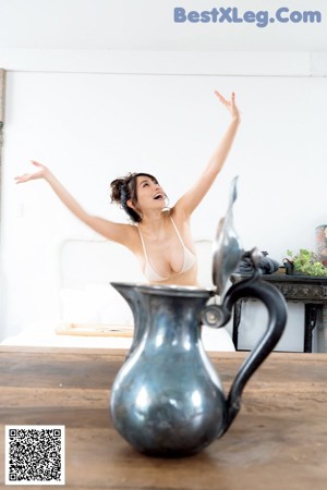 A naked woman sitting on a couch holding up a picture frame.