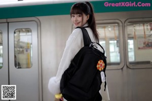 A woman in a school uniform standing on a train track.