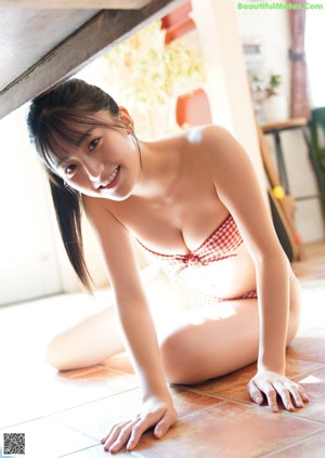 a japanese woman in a white bikini sitting on a bed