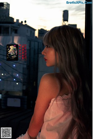 A woman sitting on top of a bed next to a window.