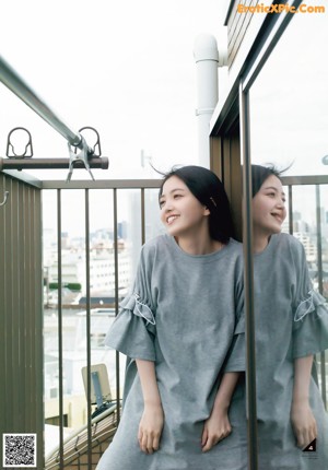 A woman in a green sweater is looking out a window.