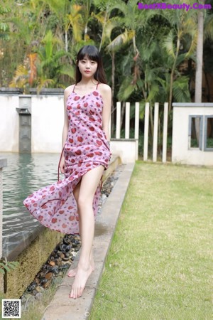 A woman in a pink dress sitting on a tree stump.