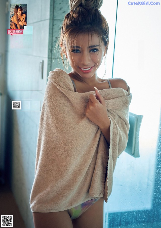 A woman in a towel standing in front of a window.