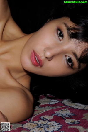 A woman laying on top of a rug next to a pillow.