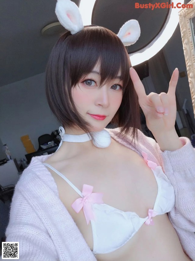 A woman in a white bra and bunny ears posing for a picture.